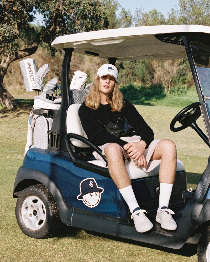 Sitting in a golf cart, Igor Haenel appears in the Jimmy Choo x Malbon collection campaig