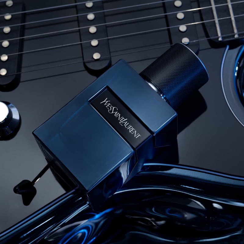 In a captivating fragrance advertisement, the sleek Yves Saint Laurent Y Elixir bottle takes center stage, resting atop a glossy guitar.