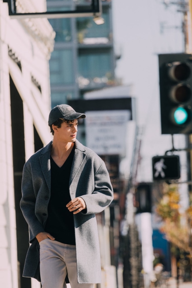 On the move for Reserved's spring 2024 campaign, Pablo Kaestli sports a relaxed overcoat and jeans with a cap.