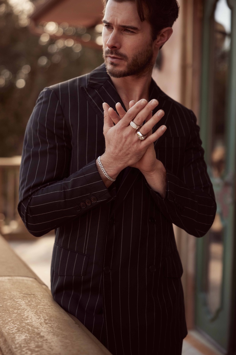 Alex Prange models Smiling Rocks jewelry, his hands adorned with statement rings and a chain bracelet on his wrist.