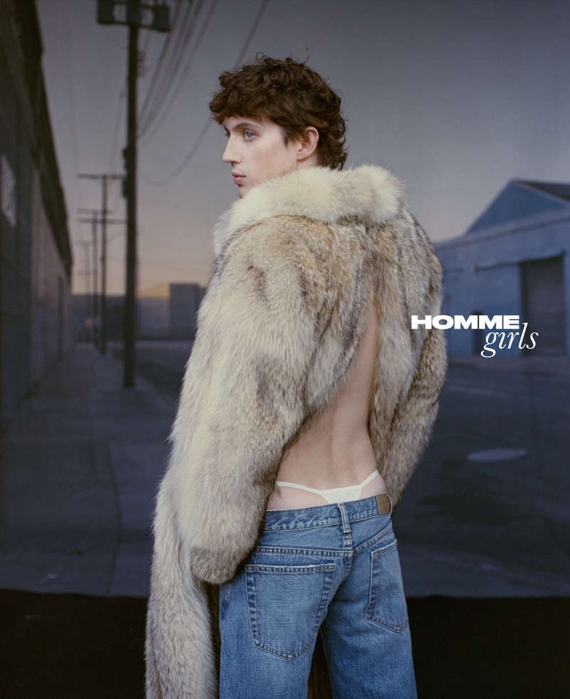 Appearing in a HommeGirls photoshoot, Troye Sivan wears a Puppets and Puppets faux fur jacket with Raimundo Langlois faded bootcut jeans, and a Los Angeles Apparel thong.