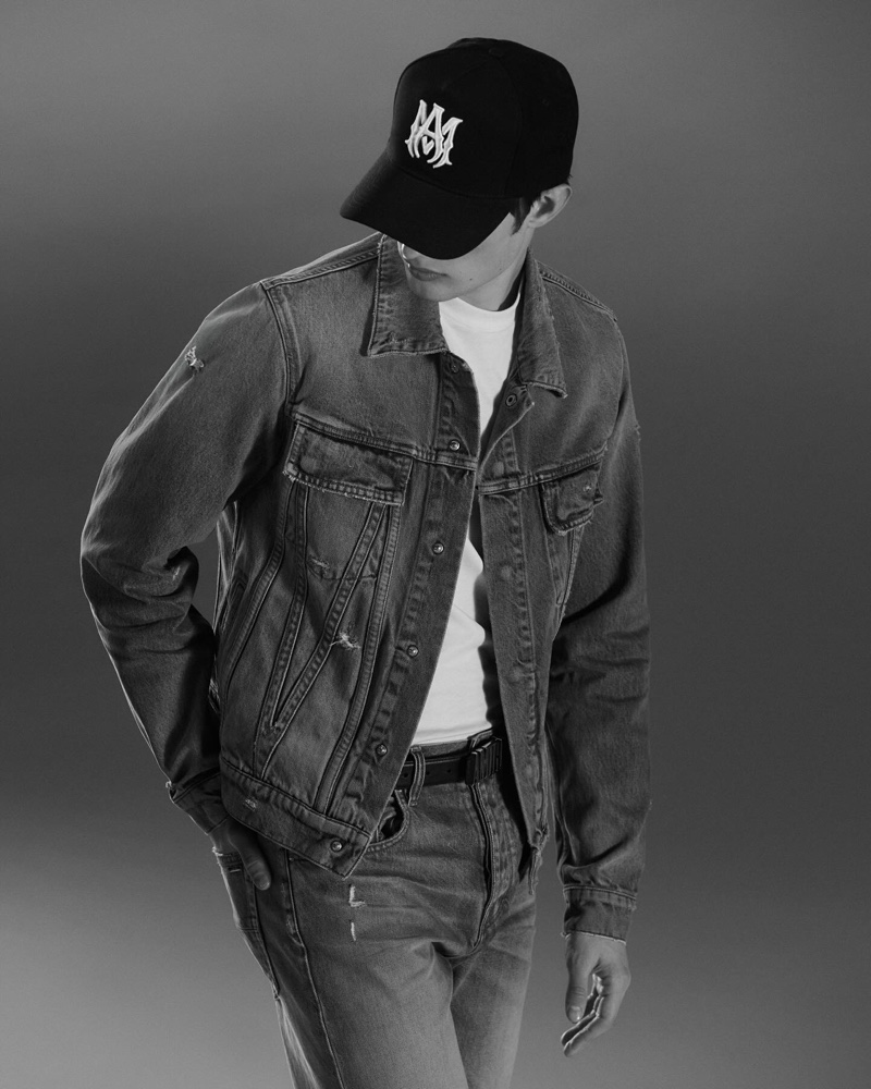 Thatcher Thornton wears a denim MA trucker jacket, trucker hat, and released hem straight jeans for the AMIRI Core campaign.