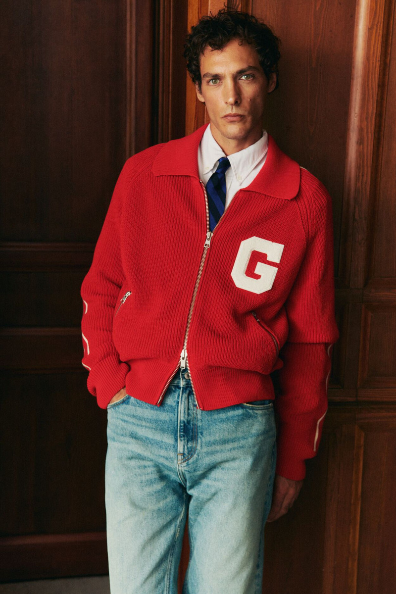Model Pierre-Benoit Talbourdet wears a red GANT tracksuit jacket over a shirt and tie with jeans. P