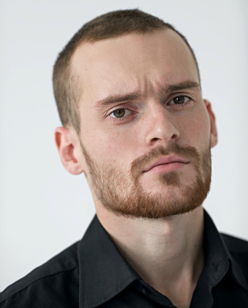 Man with a grown-out buzz cut showing short uneven hair and natural regrowth.