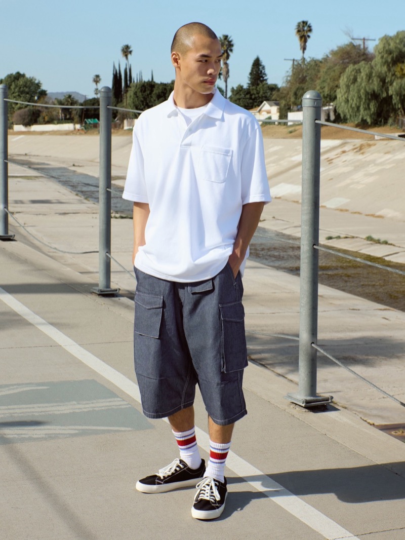 Model wears a white polo shirt with utility shorts