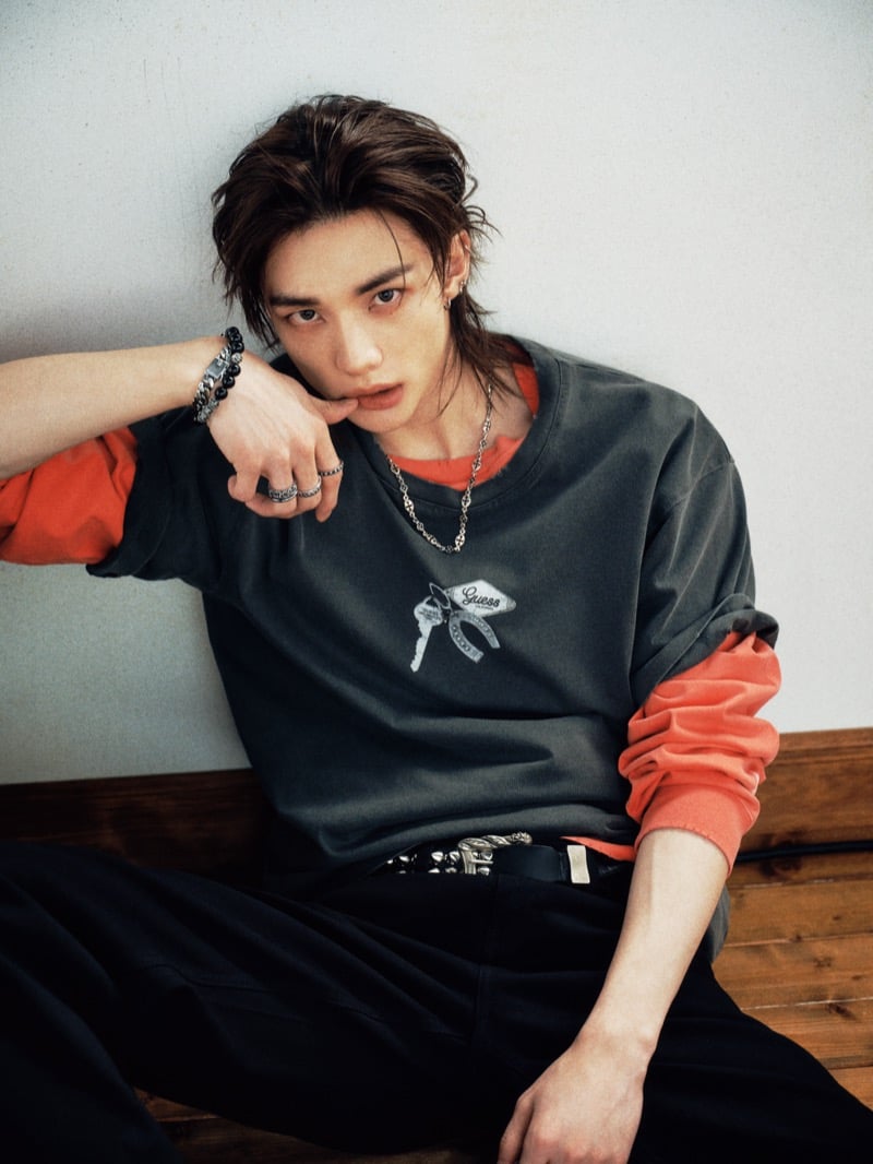 Hyunjin wears a graphic black T-shirt layered over a red long-sleeve top with black jeans