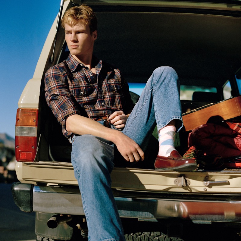 Model sits in the trunk of a vintage Land Cruiser, wearing a Madras plaid western shirt with jeans from J.Crew