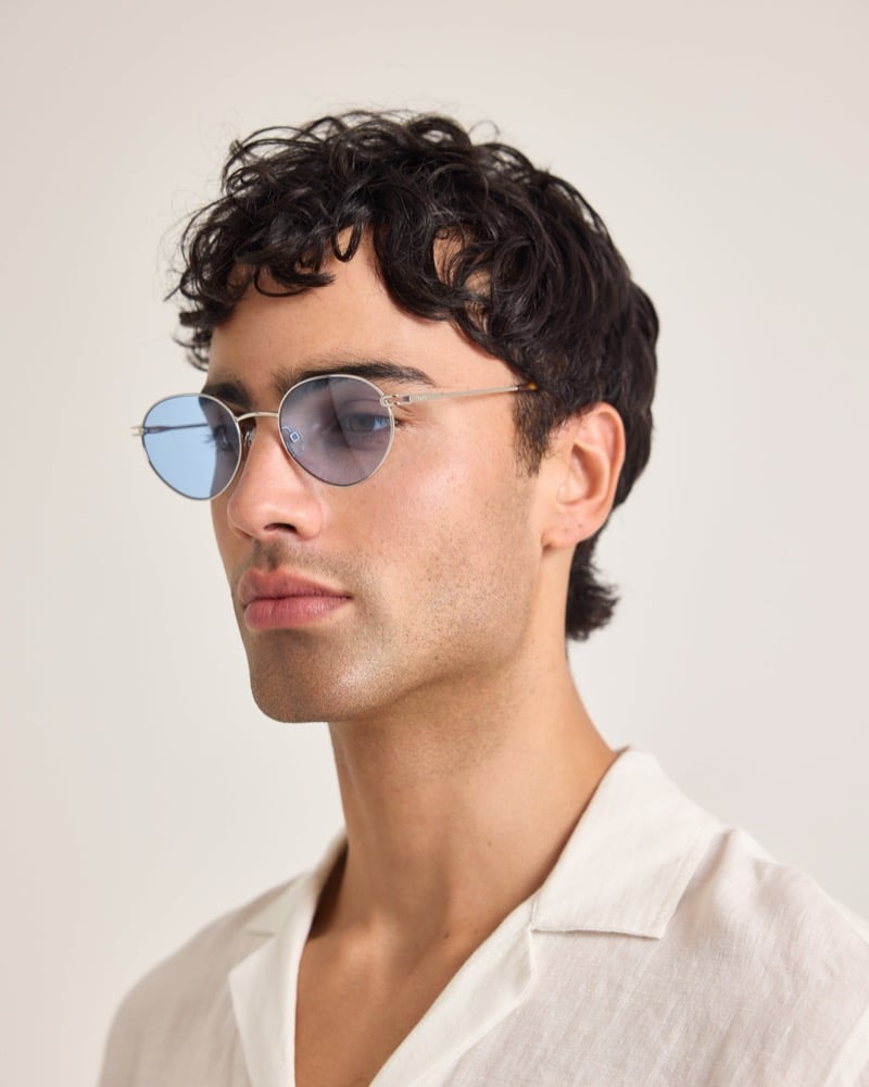 Model wears round sunglasses with a silver metal frame