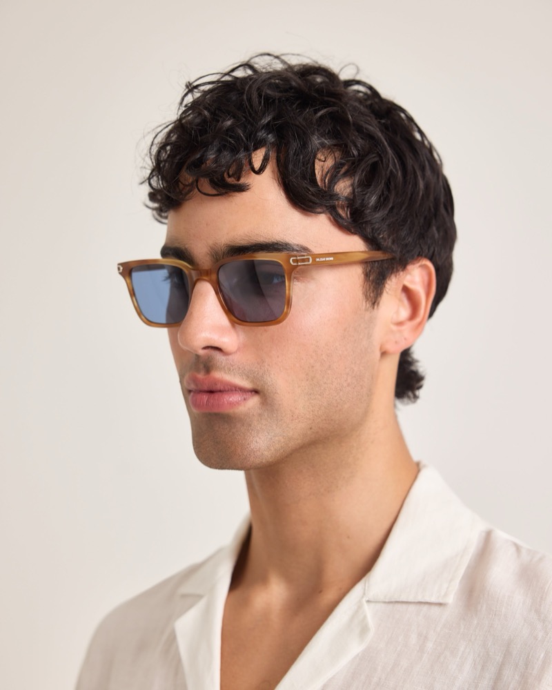 Model wears sunglasses with amber-colored frames