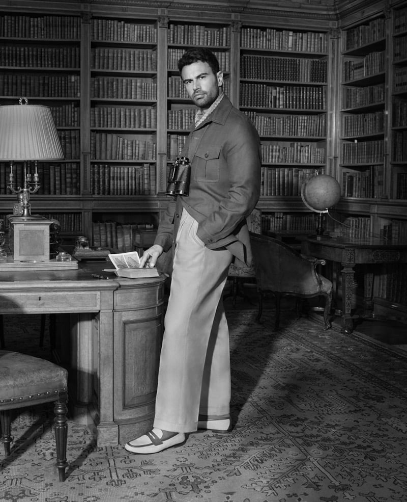 Theo stands in a manor library wearing a casual overshirt, wide-leg trousers, and linen Rother loafers with leather detailing