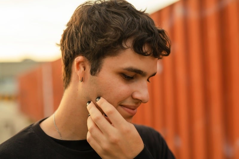 Side profile of a young man wearing black nail polish