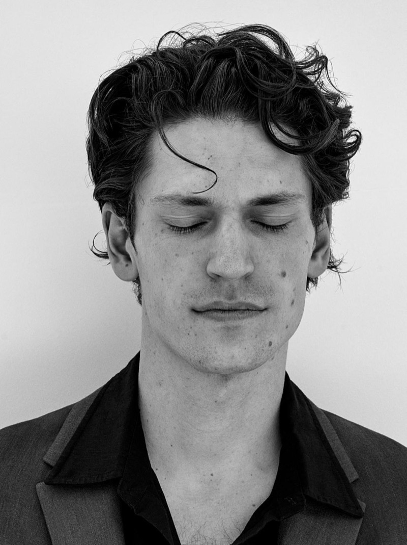 Justin in a black and white close-up portrait wearing a dark blazer