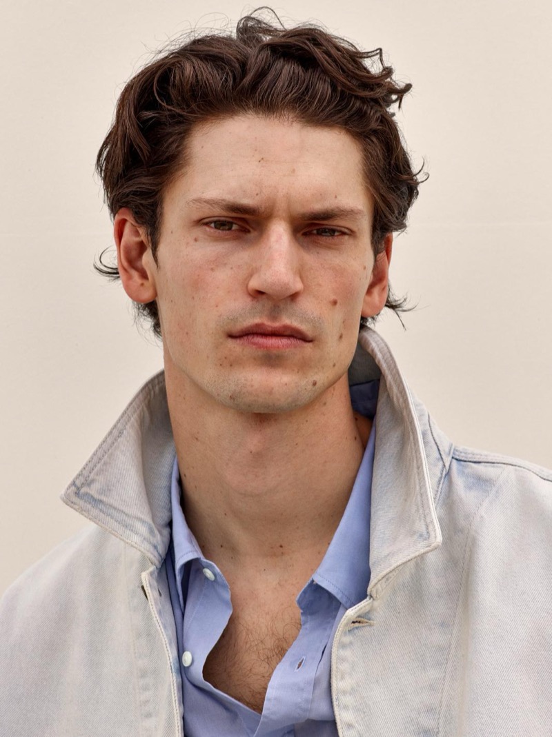 Justin in a close-up portrait wearing a washed denim jacket over a blue shirt