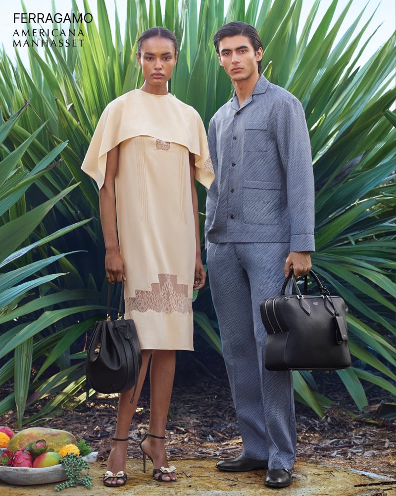 Akbar wears a Ferragamo grey pajama-style shirt and trousers with a leather bag alongside Ana in a camel poncho dress