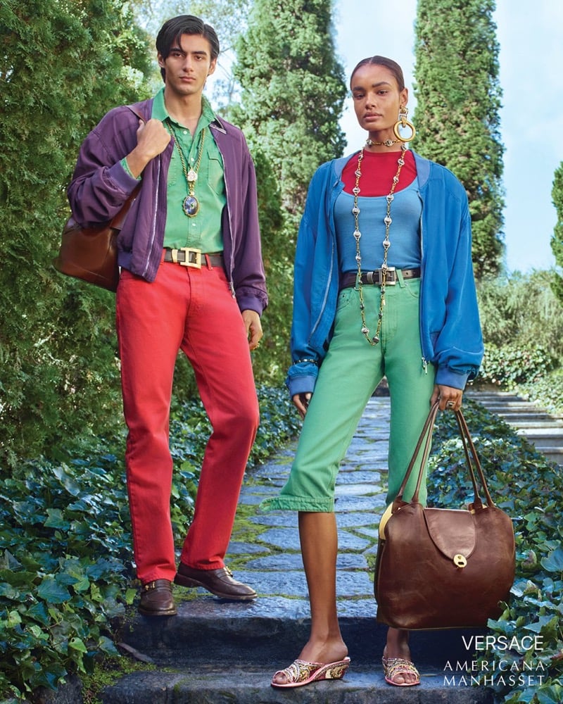 Akbar wears a Versace purple jacket a green shirt and red trousers alongside Ana Beatriz in a blue jacket and green pants