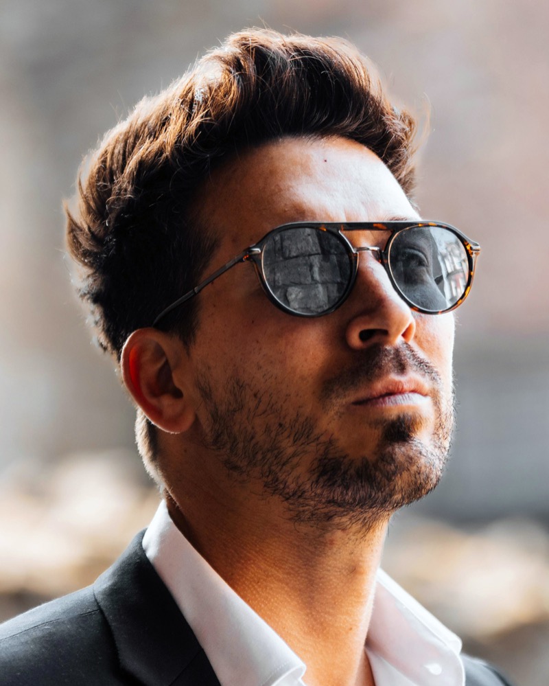 Man wearing aviator tortoiseshell sunglasses with a suit and open collar