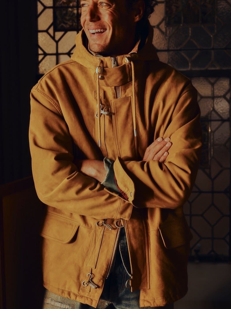 Jackson smiles in a nubuck leather firefighter's jacket with drawstring toggles, metal clasps, and patch pockets for Banana Republic's Archive Reissue collection