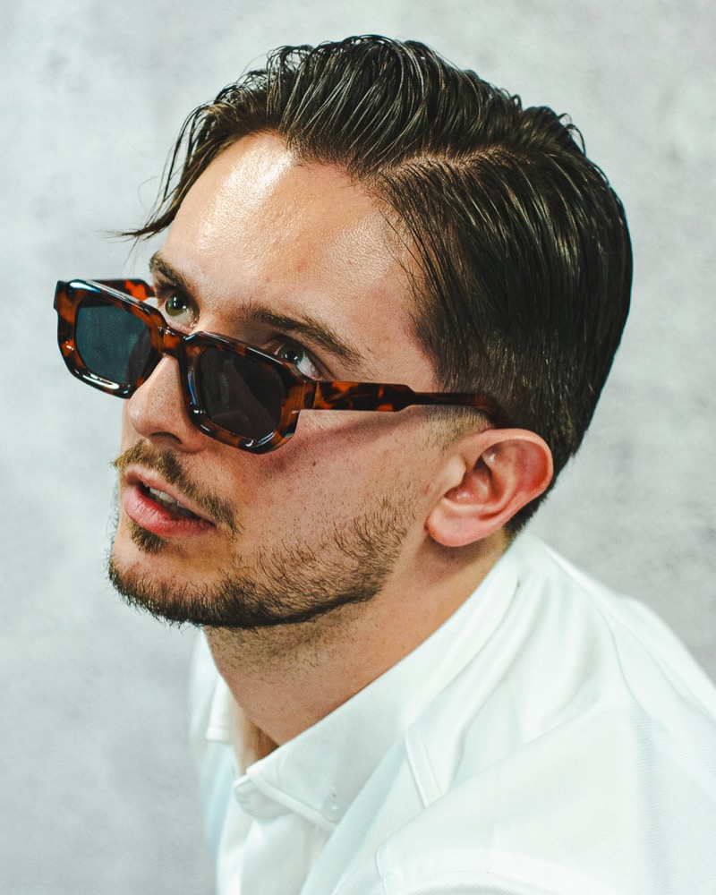 Man wearing bold chunky tortoiseshell sunglasses with a white shirt