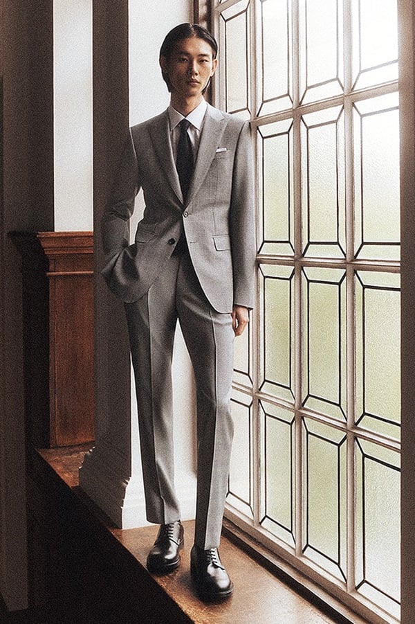 Taemin stands by a window in a pale gray BOSS Made to Order suit