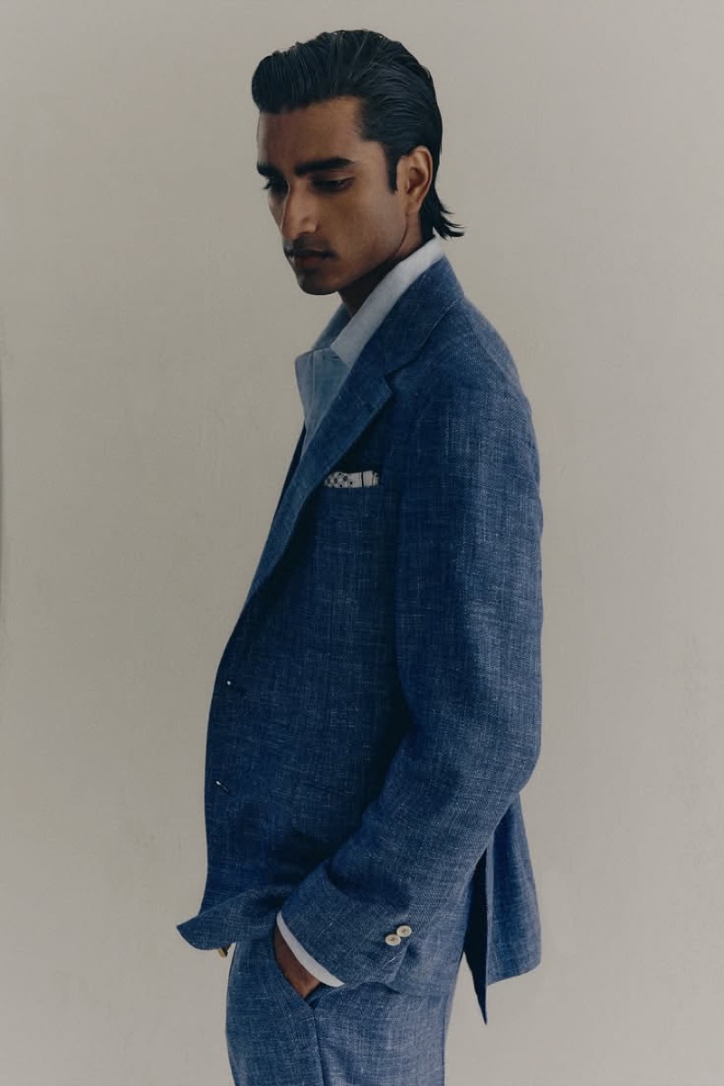 Jeenu wears an air-blue linen suit with a pale shirt and pocket square in profile