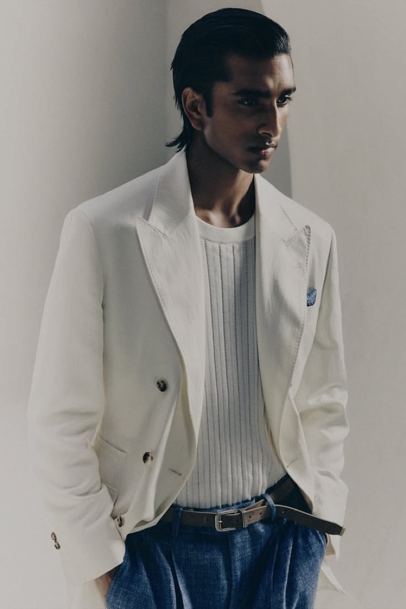 Jeenu wears a white blazer over a ribbed crew neck with blue linen trousers and a brown belt