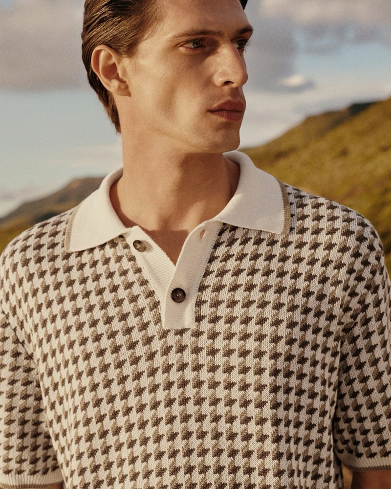 Close-up of Edoardo in a cream and brown houndstooth knit polo with a ribbed collar, set against a hillside, for Canali's spring-summer 2026 campaign