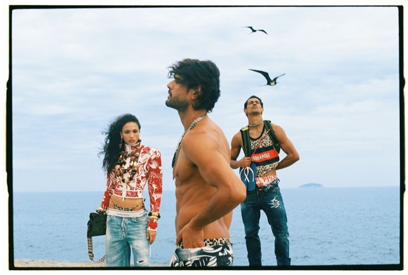 Marlon stands shirtless in printed shorts in front of a female model in a red hibiscus print top and faded jeans and a Jonas Barros in a red graphic tank, distressed jeans for Dsquared2's spring-summer 2026 campaign