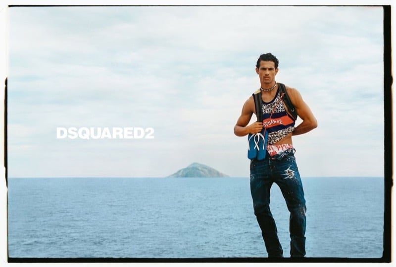 Jonas Barros stands on a rocky coastline in a red graphic Dsquared2 tank and distressed jeans for Dsquared2's spring-summer 2026 campaign