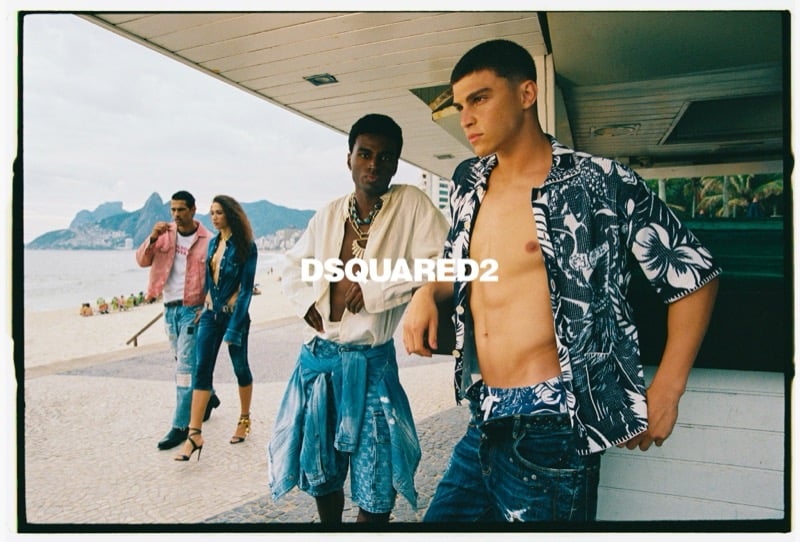 Felipe stands at a beachside cabana in an open dark Hawaiian print shirt and distressed jeans beside Matheus in an open white shirt with denim shorts and chains for Dsquared2's spring-summer 2026 campaign