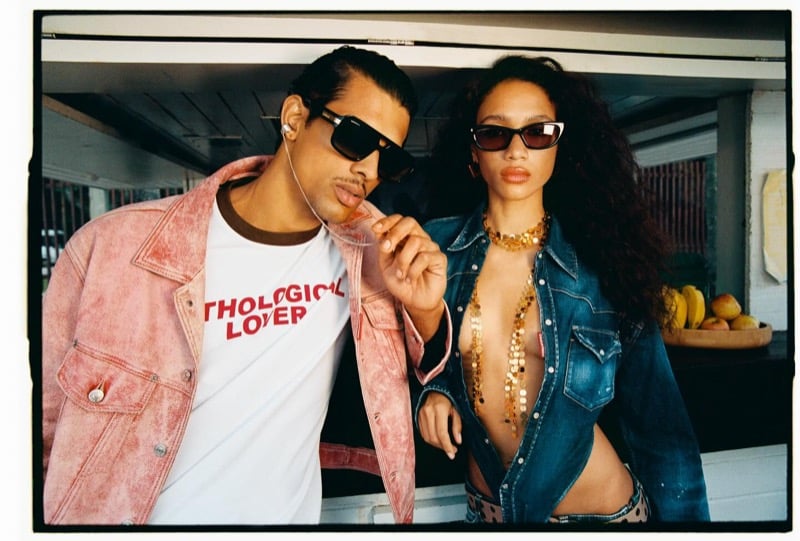 Jonas leans in a red cracked leather jacket over a white graphic tee beside a female model in an open denim trucker jacket layered over gold chains for Dsquared2's spring-summer 2026 campaign