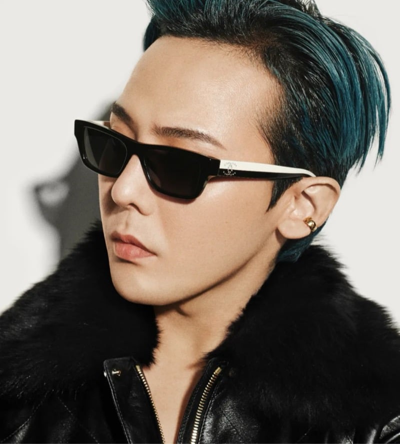 G-Dragon wears two-tone Chanel black and cream rectangle sunglasses with a double C emblem on the arm, paired with a black leather and shearling jacket