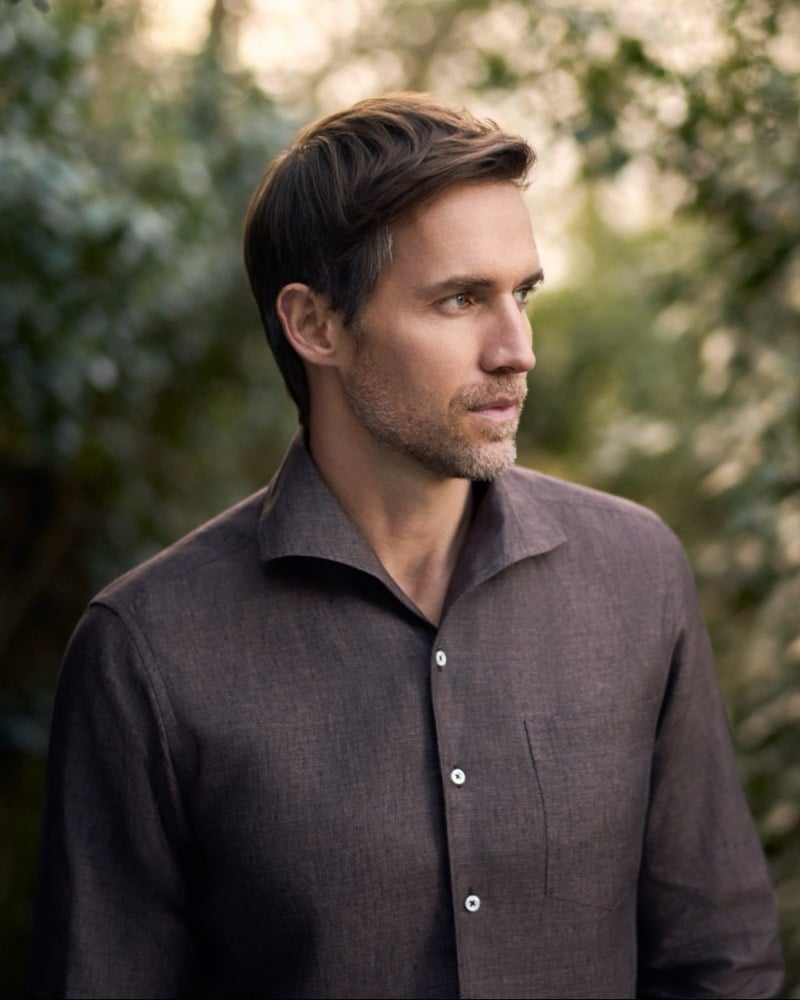 Close-up of Andrew in a brown linen shirt against soft garden foliage for Huntsman's spring-summer 2026 collection