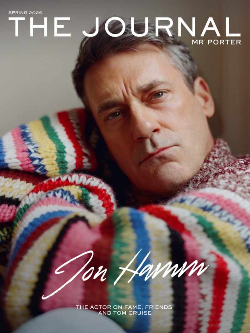 Jon wears a multicolor striped polo sweater and bootcut jeans