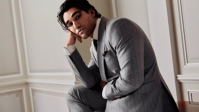 Josh Heuston sits in a gray pinstripe BOSS Made to Order double-breasted suit