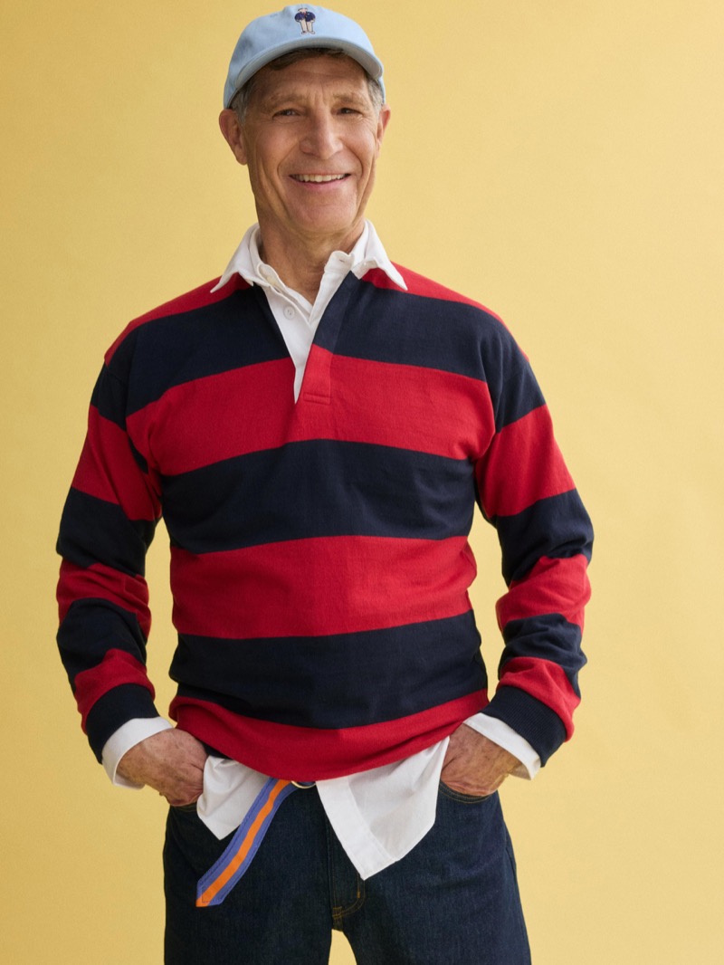Michael wears a J.Press x Alex Mill red and navy block-striped rugby shirt over a white shirt with dark jeans, a trailing striped D-ring belt, and a light blue J.Press baseball cap