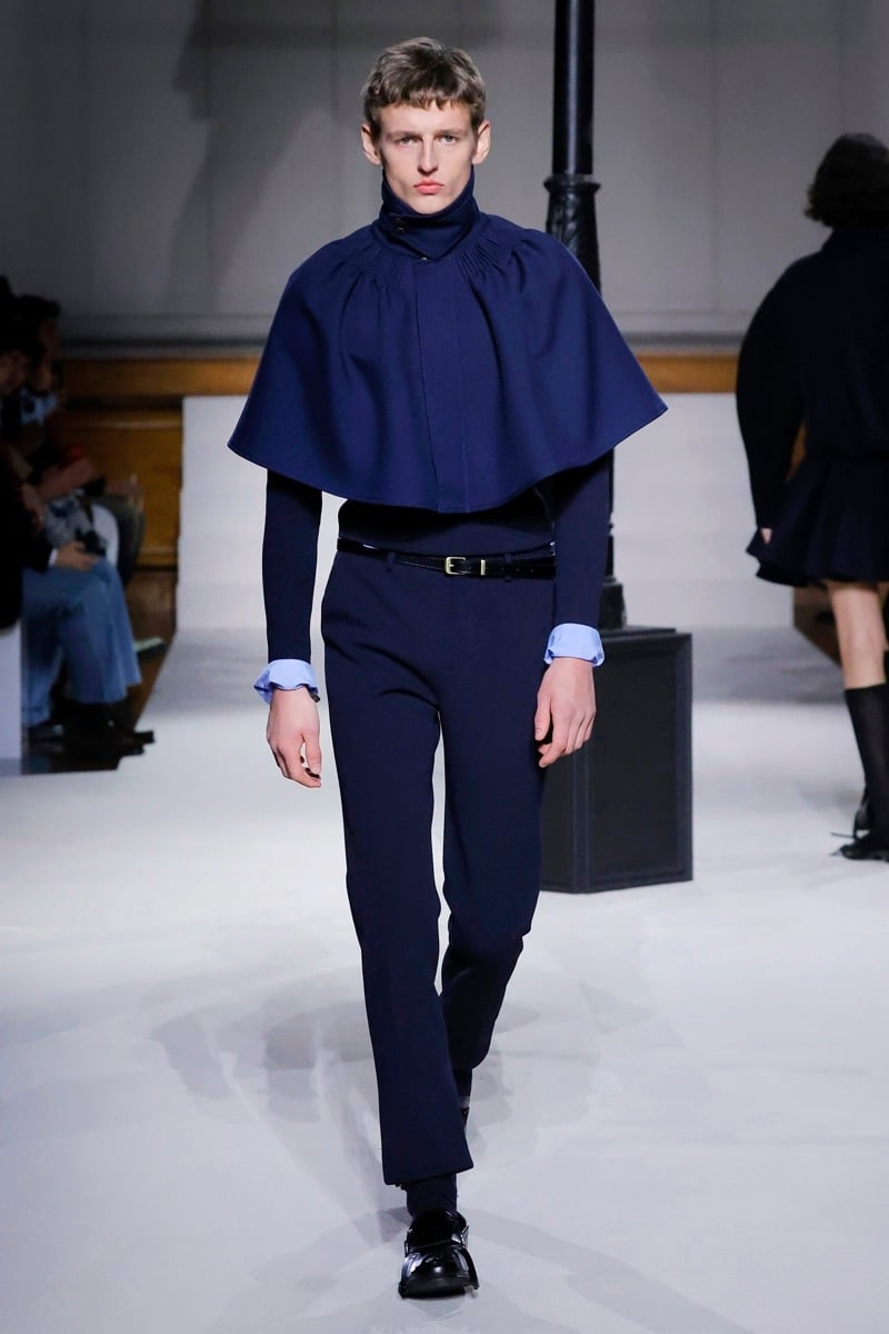 Kent & Curwen fall-winter 2026 navy gathered cape with pleated high collar over a light blue shirt and navy slim trousers
