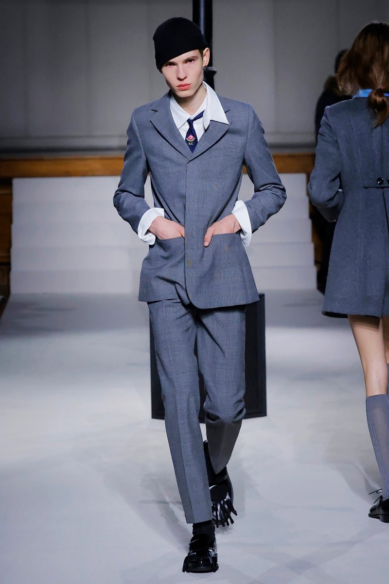 Kent & Curwen fall-winter 2026 gray glen plaid suit with wide peak lapels and oversized white shirt cuffs with a striped tie and black skull cap
