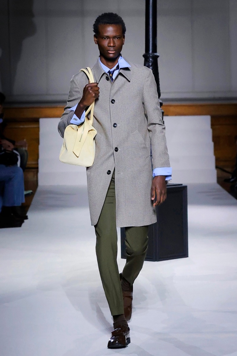Kent & Curwen fall-winter 2026 gray single-breasted overcoat over a light blue shirt with olive trousers and a cream leather bag