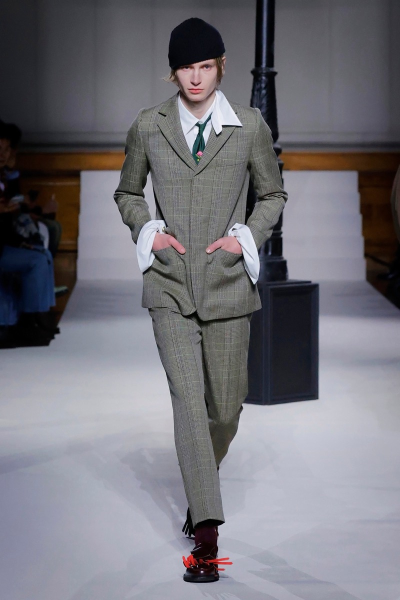 Kent & Curwen fall-winter 2026 olive glen plaid suit with wide peak lapels and oversized white shirt cuffs with a green tie and black skull cap