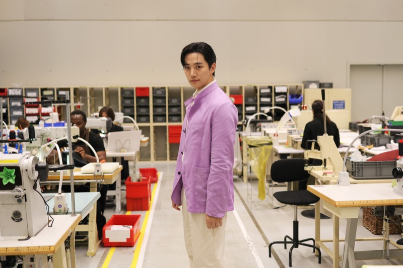 Jun-ho stands on the floor of the Berluti Manifattura as artisans work at stations behind him