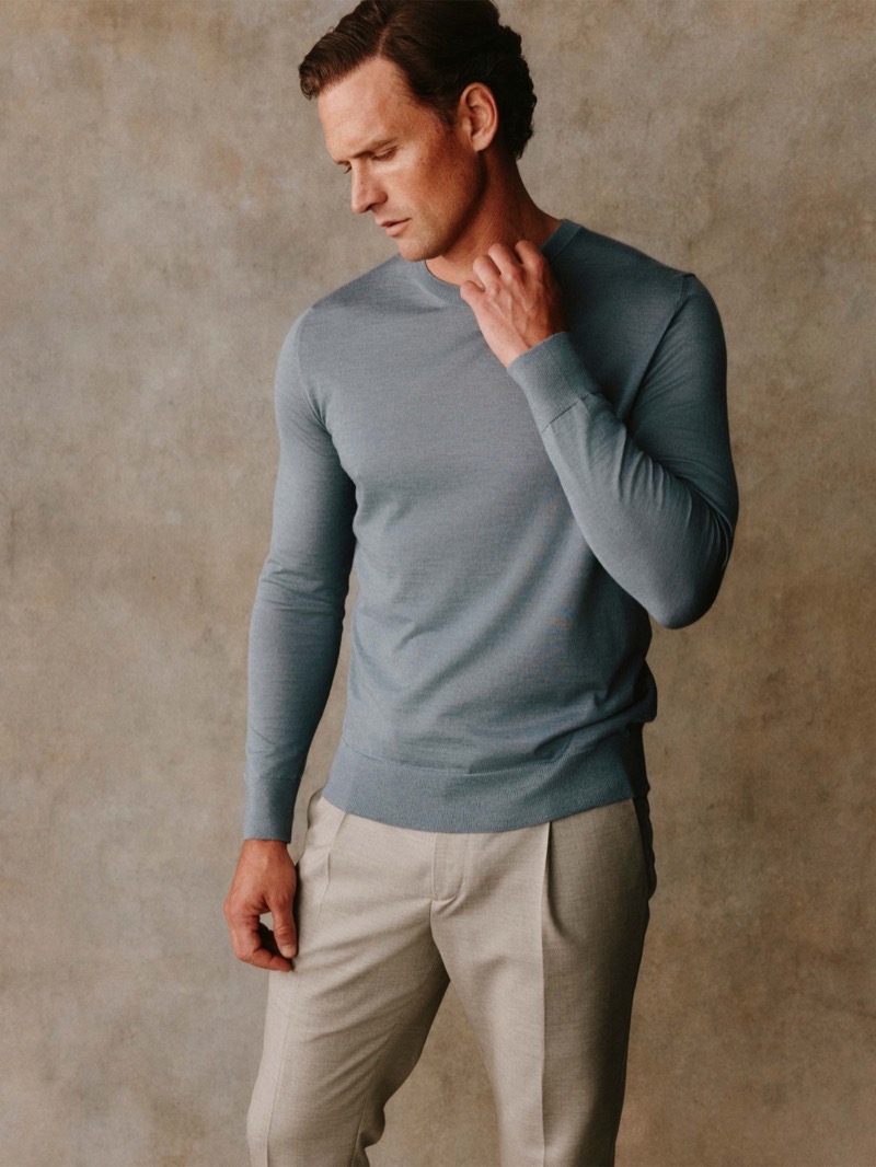 Guy wears a dusty blue crewneck sweater with stone linen trousers