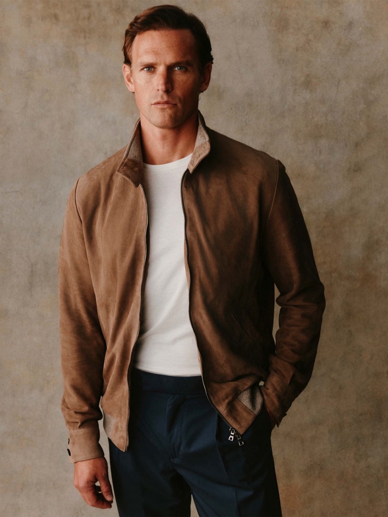Guy wears a tan suede Harrington jacket over a white tee with navy trousers