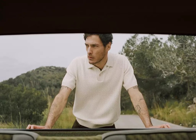 Pierre-Benoit wears a white waffle-knit polo viewed through a car sunroof