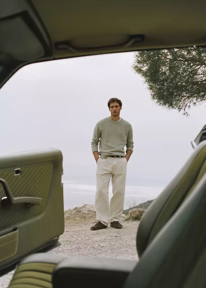 Pierre-Benoit wears a sage lace-pattern sweater with white trousers framed through a car door
