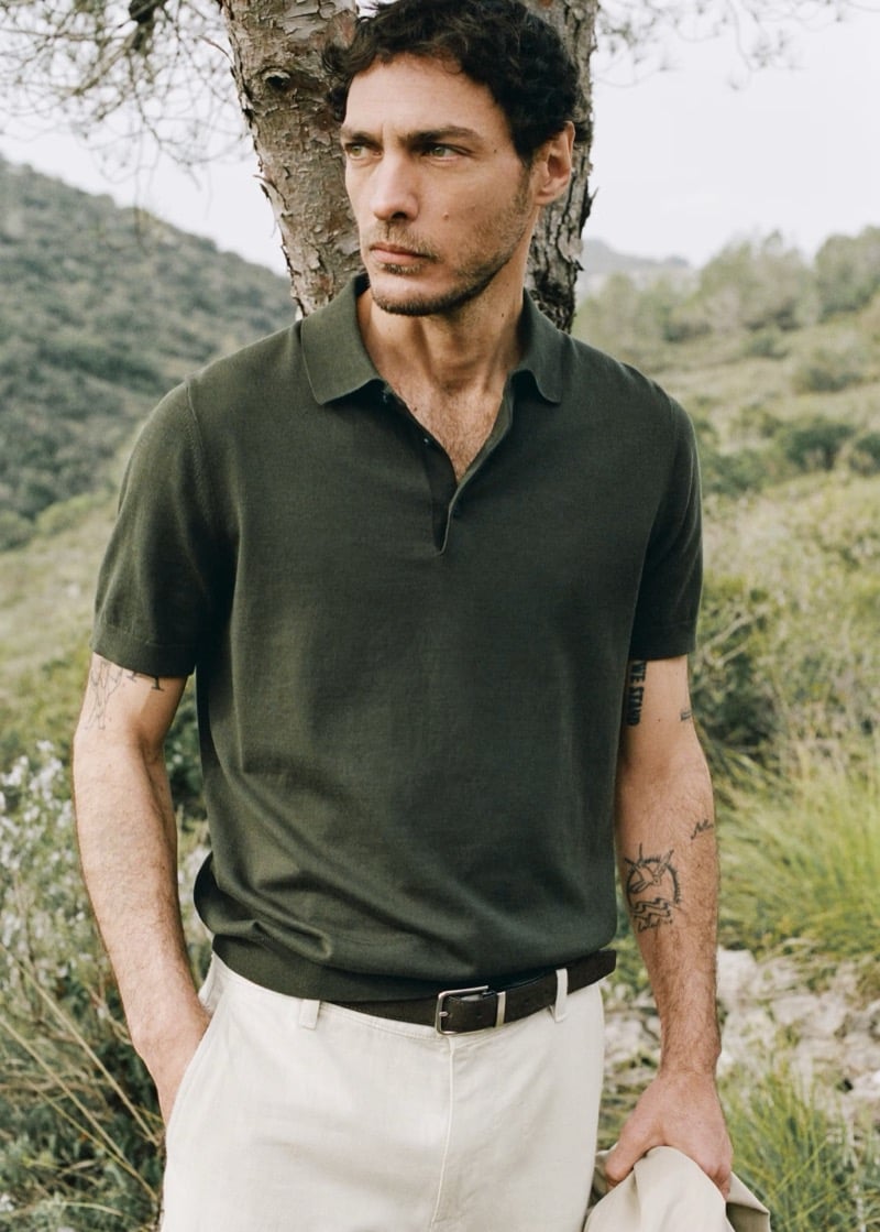 Pierre-Benoit wears a dark sage fine-knit polo with cream trousers and a leather belt