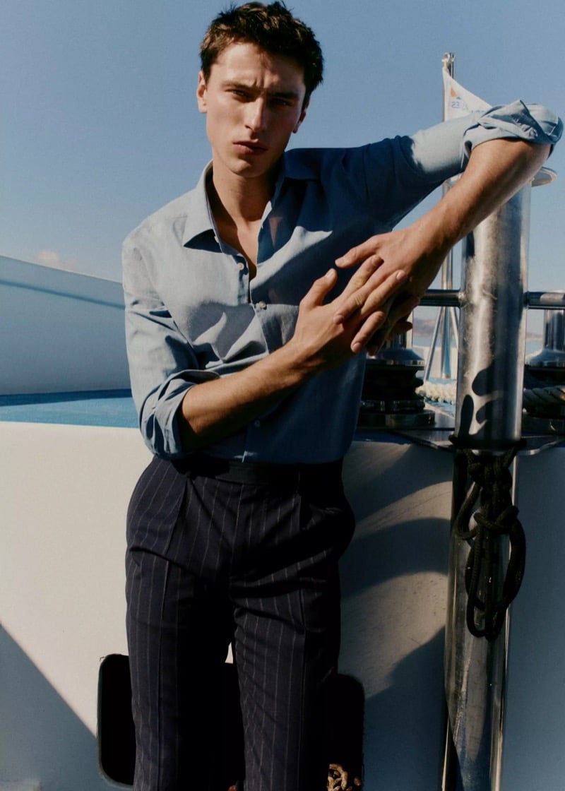 Clément leans against a yacht rail in a denim-blue shirt with sleeves rolled up and dark navy pinstripe trousers for Mango Selection's spring-summer 2026 campaign