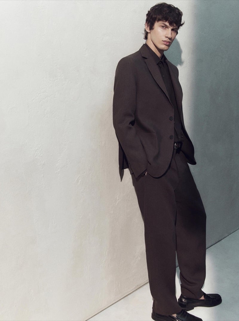 Kaplan wears a brown suit with a matching shirt and leather loafers