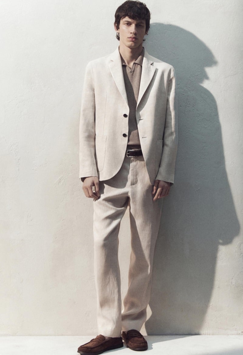 Kaplan wears a cream linen suit with a tan polo and brown suede loafers