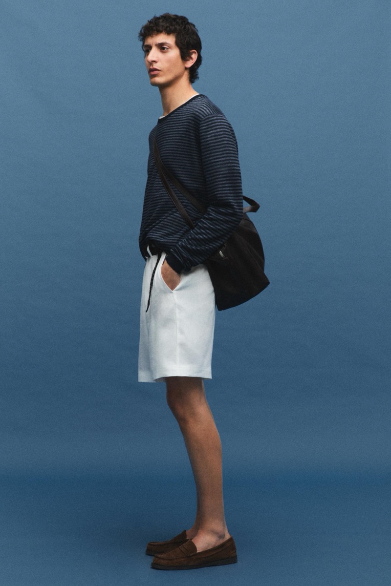 Takfarines wears a navy striped long-sleeve tee with white shorts and a leather bag