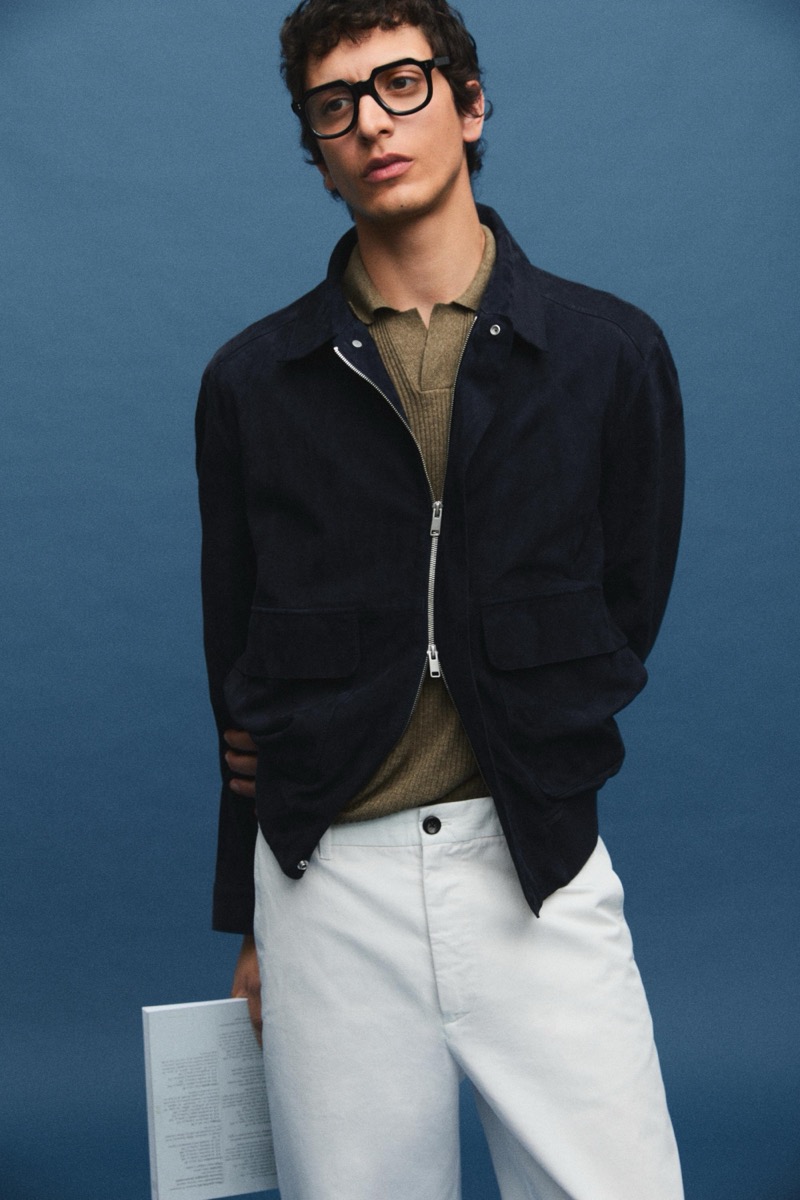 Takfarines wears a suede zip jacket over a knit polo with white trousers